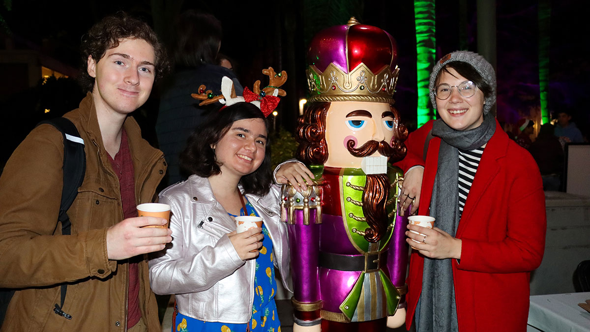 Three students standing with a human-sized nutcracker statue