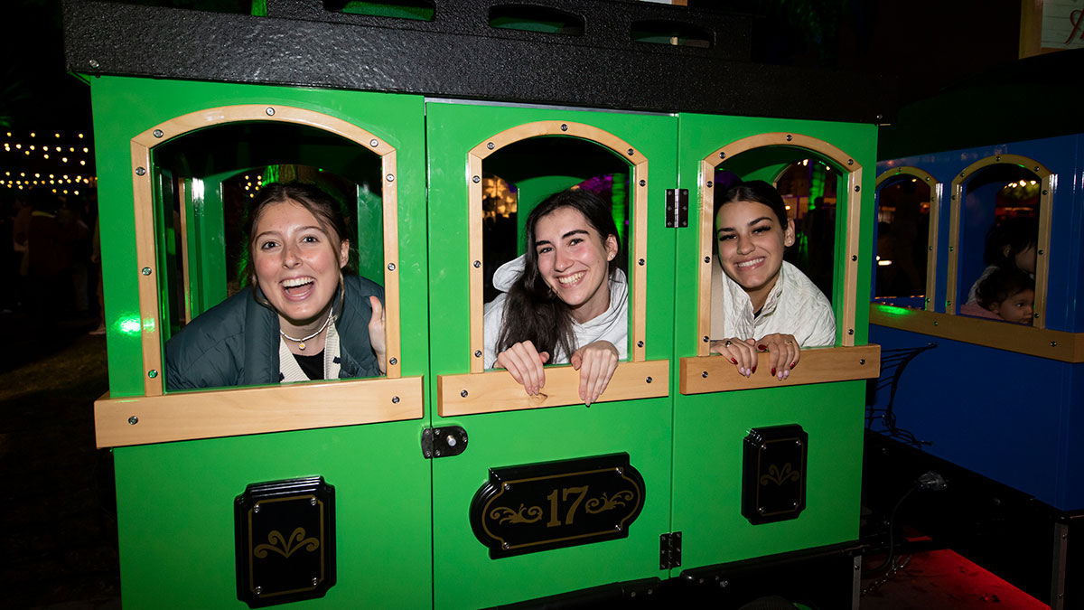 Three students sitting in a miniature train car