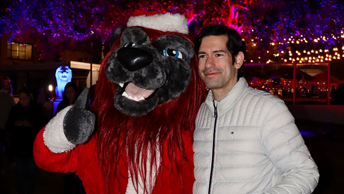 Iggy wearing a Santa costume and posing with a staff member