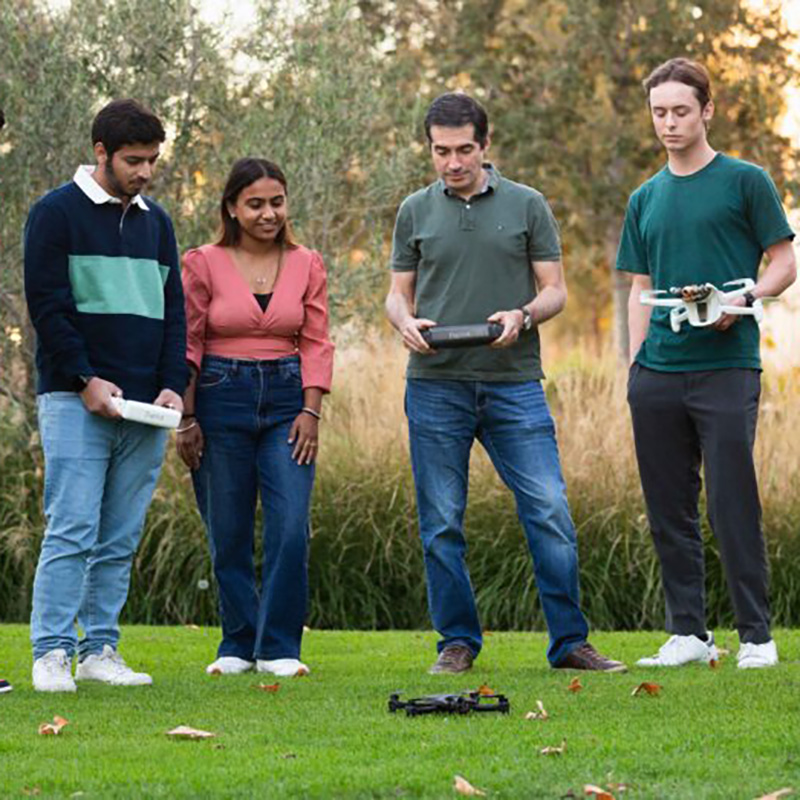 professor and students with drone on the grass