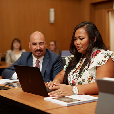 two people wearing business attire looking at a laptop