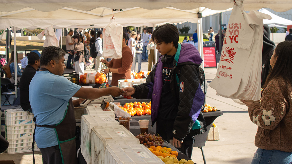 student purchasing fruit at a vendor booth