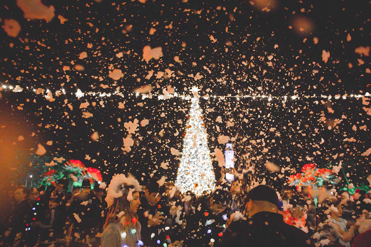 A large crowd of people celebrating in Regents Terrace with the LMU Christmas tree lit up in the distance