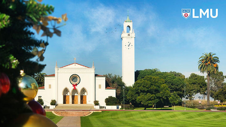 A Christmas tree in the foreground with Sacred Heart Chapel in the distance