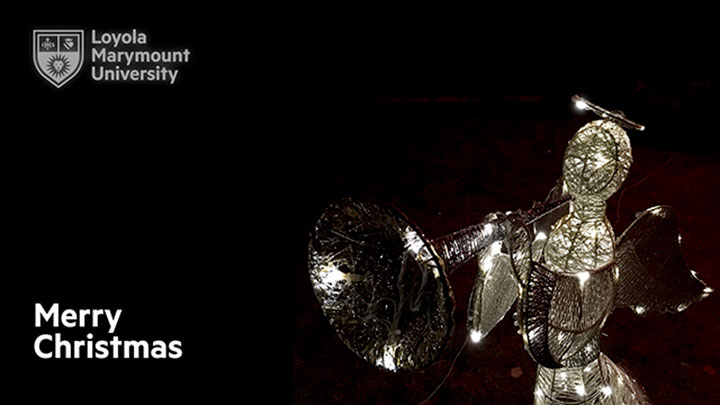 An ornate figurine of an illuminated angel blowing a horn with the words Merry Christmas