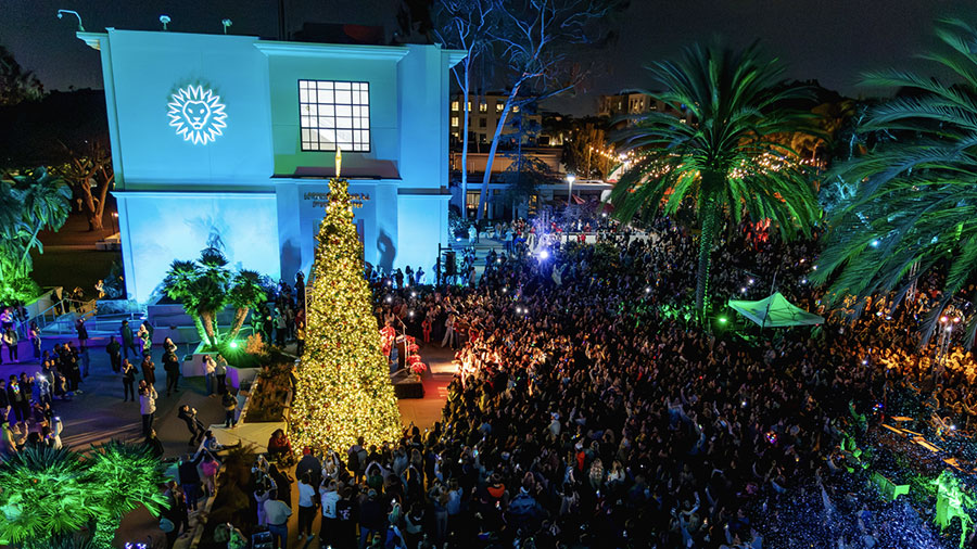 A large crowd of people encircling the newly illuminated Christmas tree in Founders Pavilion