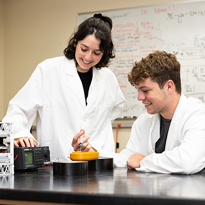 two students wearing lab coats doing research