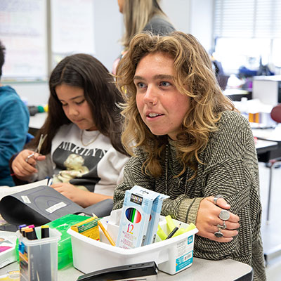 LMU student sitting next to elementary school student in classroom