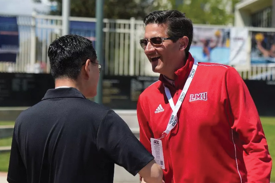 President Tom Poon shakes hands with Athletic Director Craig Pintens