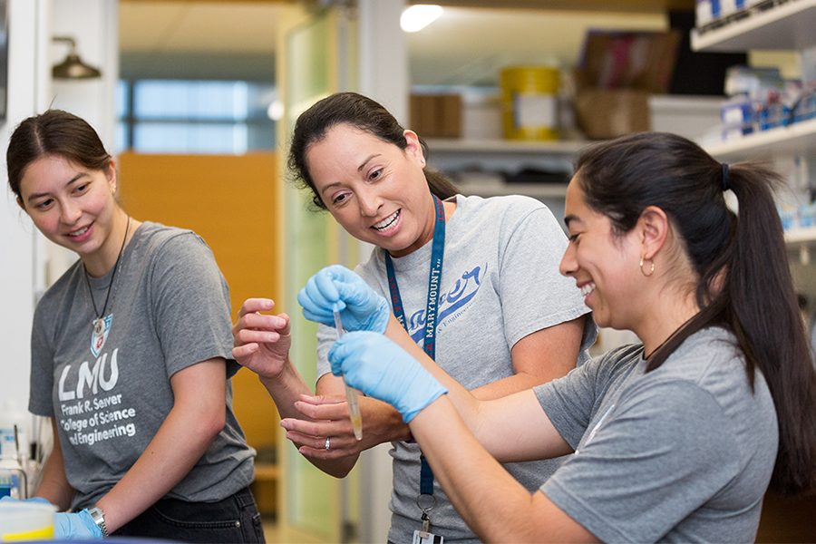 LMU biology professor Christina Vasquez shows two students how to work with mussels in the lab
