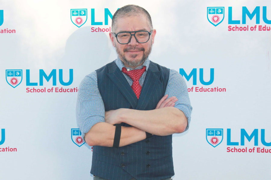 LMU Professor Will Perez in front of a school of education backdrop