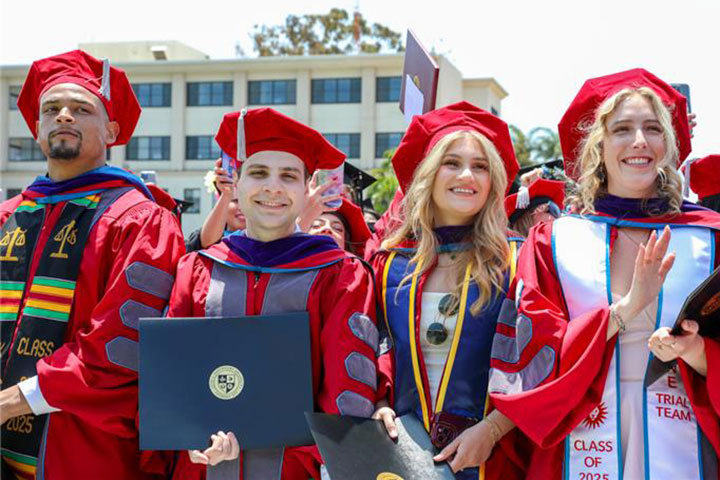 Graduates in cap and gown during commencement holding their diplomas at their seats in Sunken Garden
