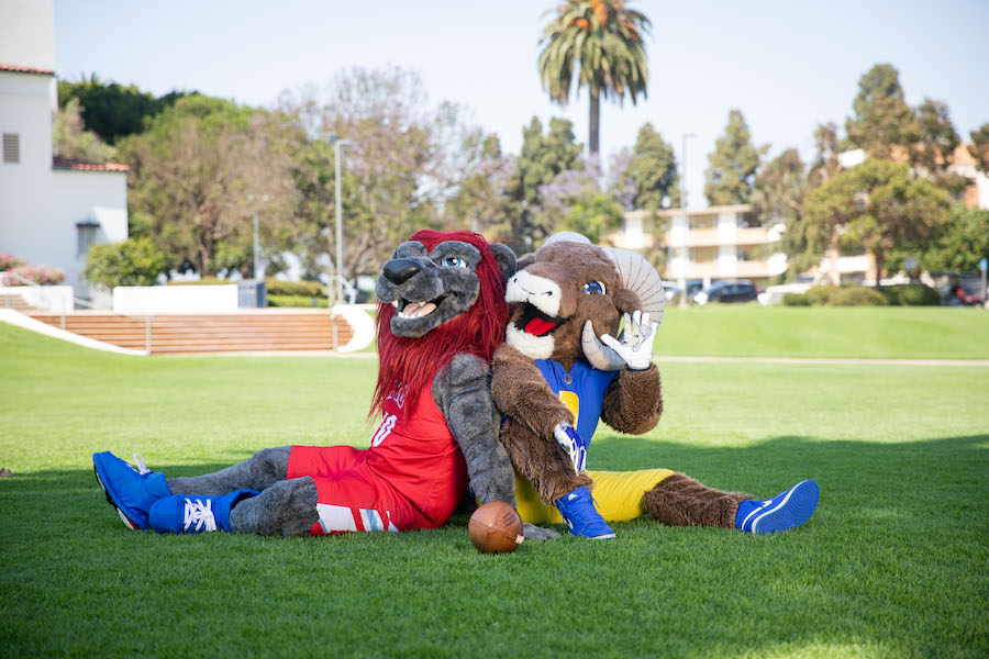 LMU mascot Iggy and Rams mascot Rampage sit back to back in Sunken Garden.