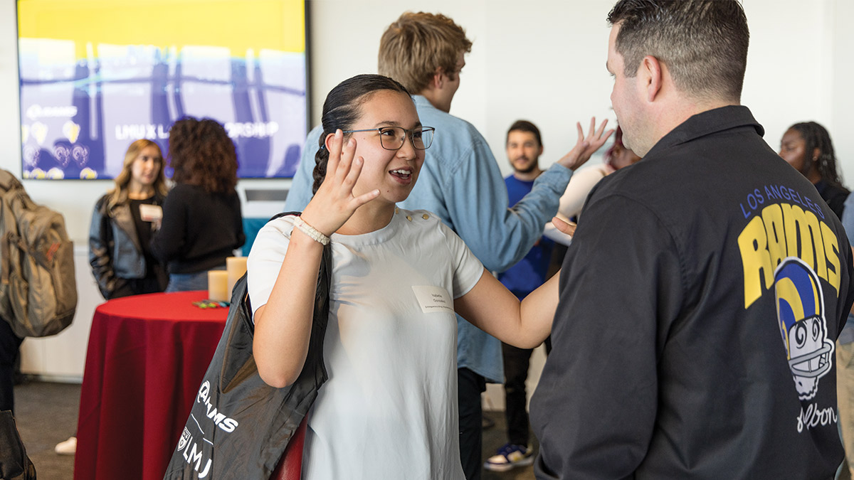 Students speaking animatedly to a L.A. Rams Employee