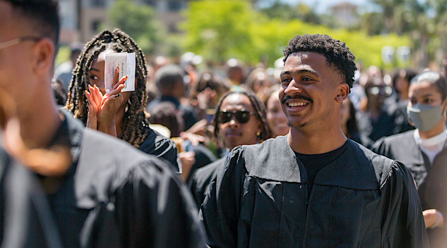 Male student at Kente graduation smiling in the crowd