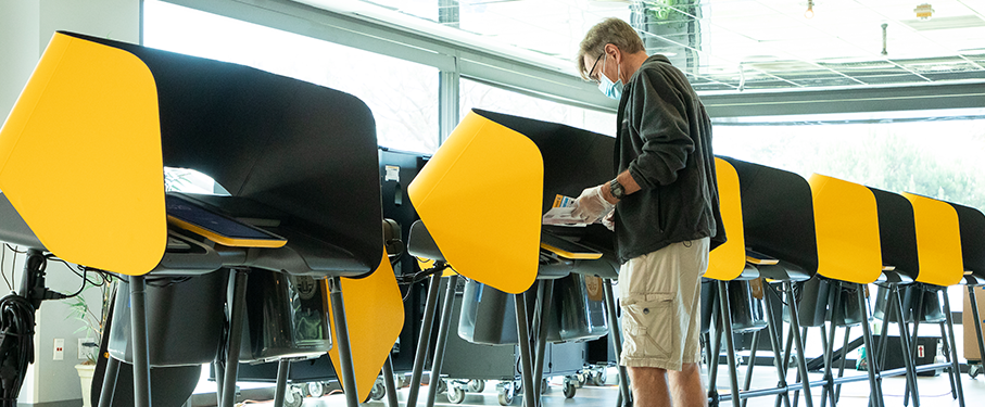 A man stands at a voting center booth inside Roski Dining Hall.